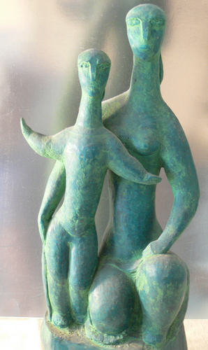 A modernist sculpture of a mother and child in a textured green patinated material, set against a neutral, softly blurred background.

