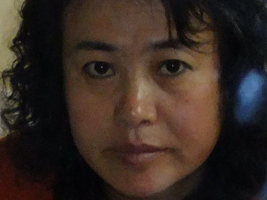 Close-up of a person with dark hair and skin, wearing headphones.


