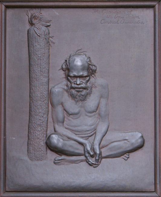 Relief sculpture of a seated figure with a staff on a stone background

